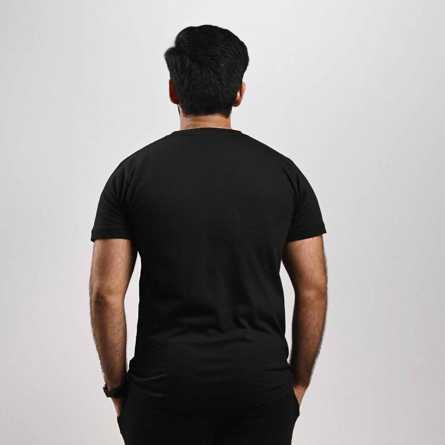 Person wearing a black t-shirt and black pants on a white background